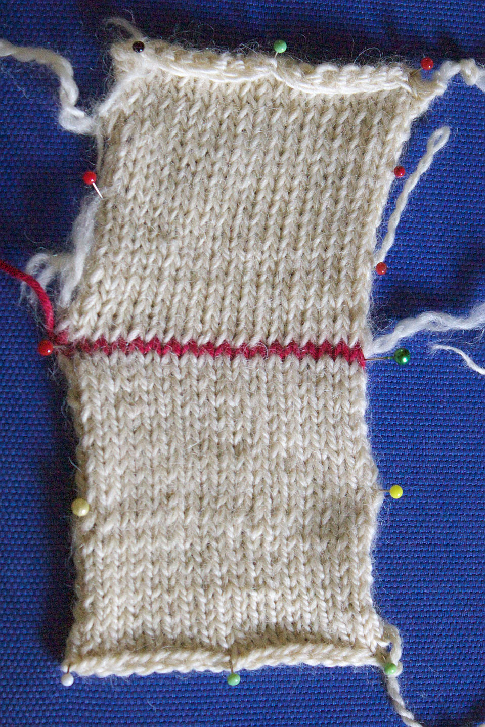 The difference between knitting with plied and non-plied yarns shows clearly after wetting the piece. Knitted with plied yarns, the fabric stays straight (bottom). It ‘leans’ when knitted with two unplied yarns held together (top)